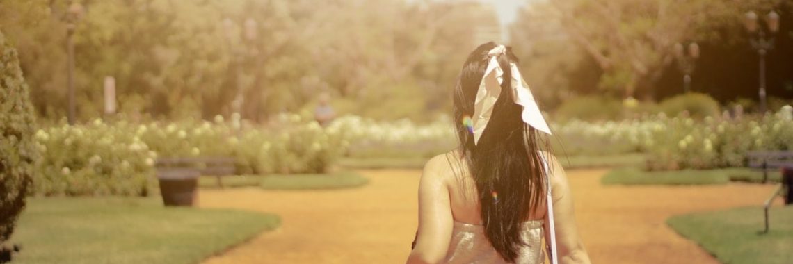 girl walking in a park holding a camera