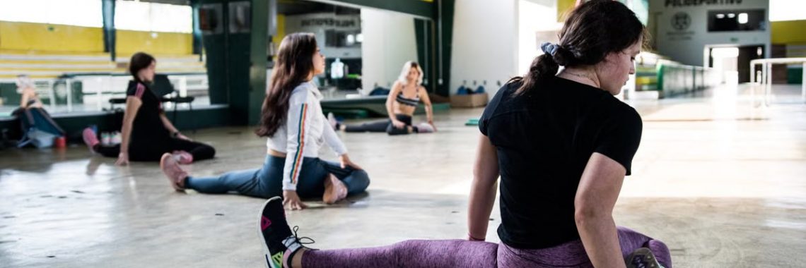 Women engaging in a group stretching session in an indoor gym.
